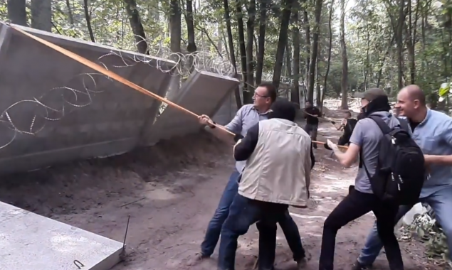 Столичные коммунальщики и активисты демонтируют забор вокруг строительства в Пуще-Водице (видео)